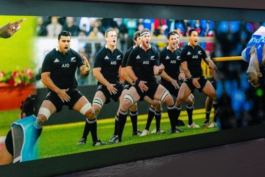 A rugby team in black uniforms with 'AIG' on the front, standing in a line on a field. 3