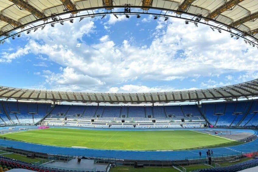 A large stadium with blue seating and a green field. 1