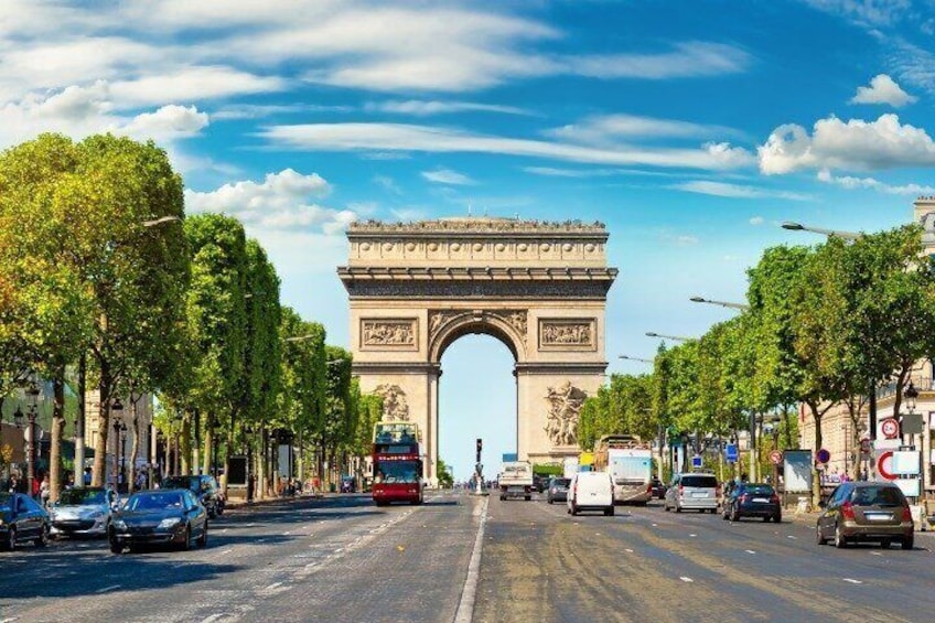 The Arc de Triomphe in Paris, surrounded by trees and vehicles on the street. 4