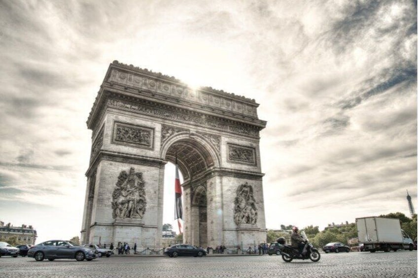 The Arc de Triomphe in Paris, with cars and a motorcycle in the foreground. 5