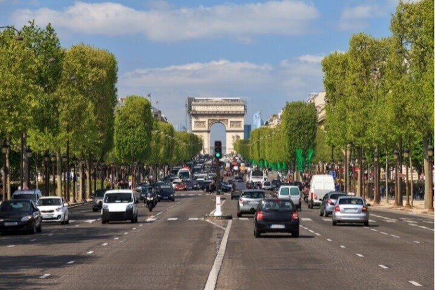 A busy urban street with cars, trees, and the Arc de Triomphe in the background. 2