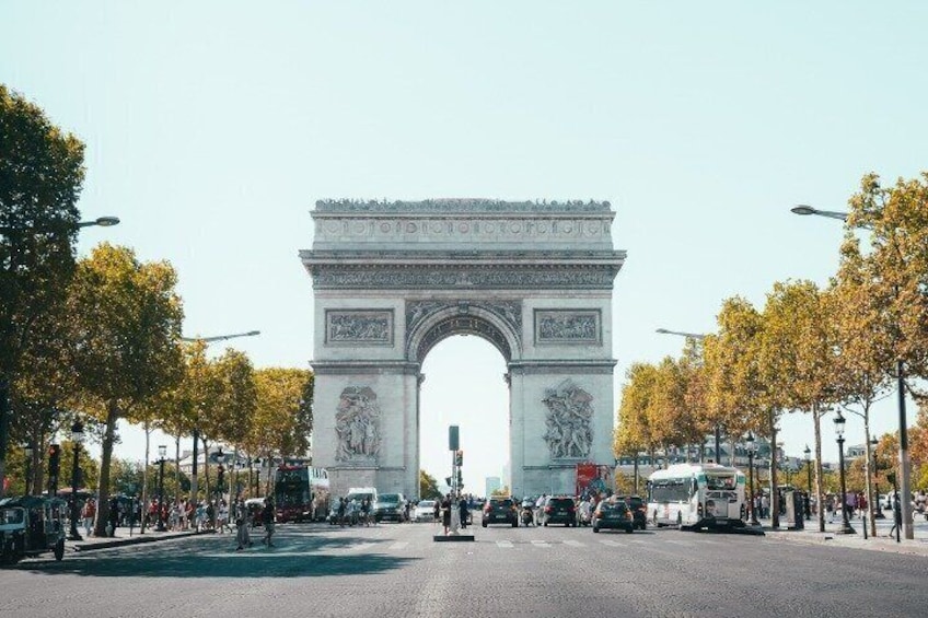 The Arc de Triomphe with a busy street in the foreground and trees lining the sides. 3