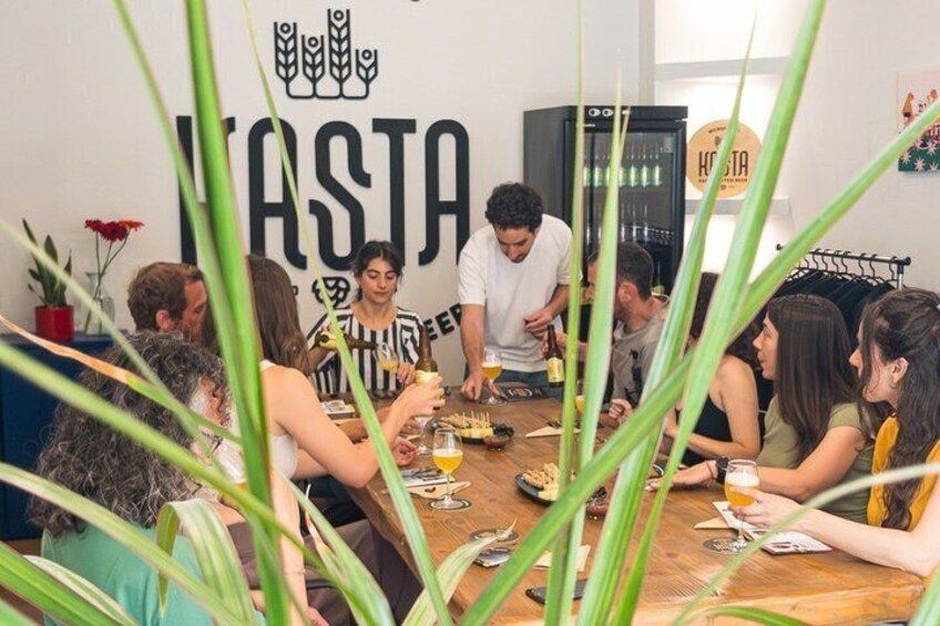 A group of people dining at a wooden table in a room with a large 'HASTA' sign on the wall. 4