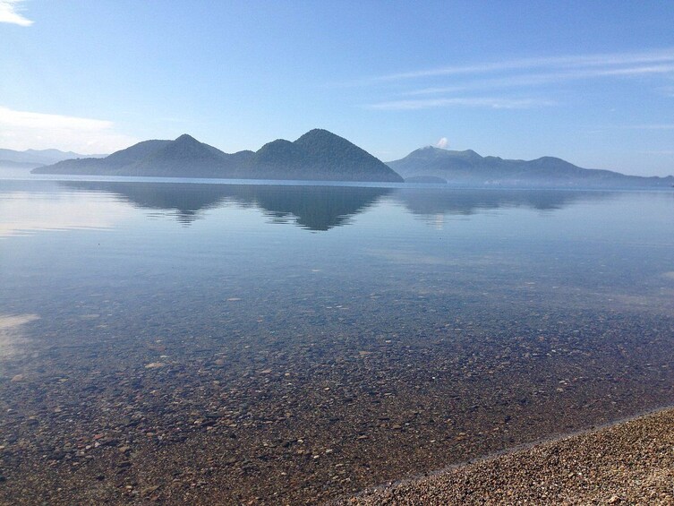 A calm lake with clear water reflecting mountains in the distance. 4