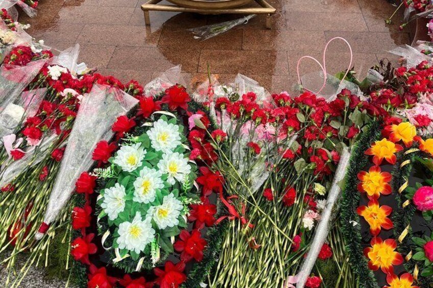 A variety of flowers in bouquets and bunches, some wrapped in plastic, displayed on the ground. 4