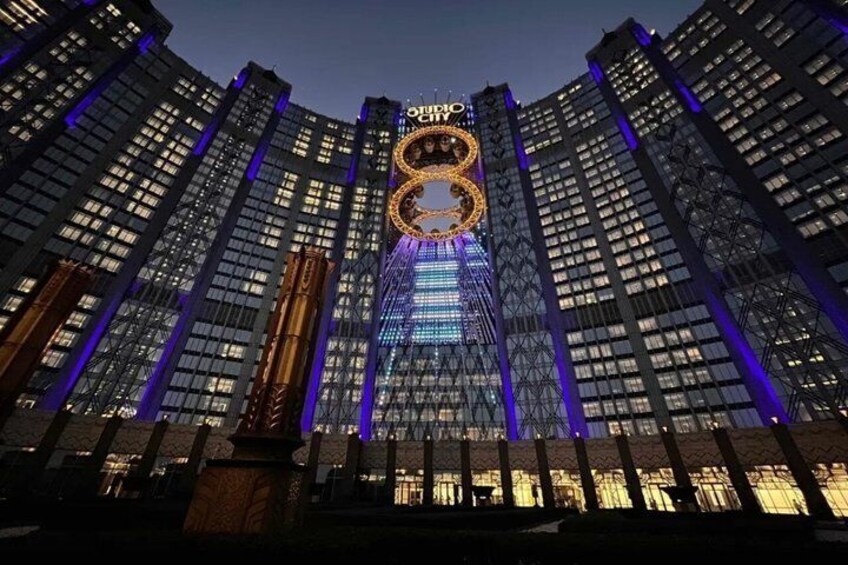 A high-rise building with illuminated signage and vertical lines of blue lighting. 1