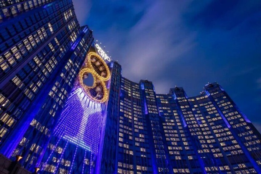 A cityscape with illuminated skyscrapers and a prominent building with a circular light display. 4