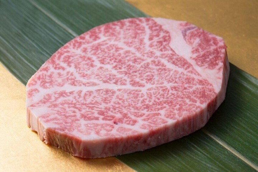 A piece of meat with a marbled texture on a green leaf. 4