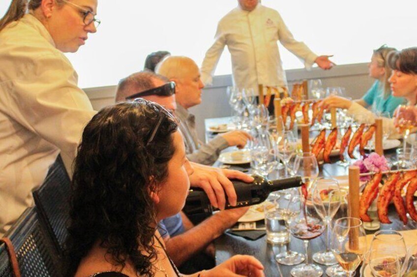 A group of people seated at a table with wine glasses and a bottle of wine. 3