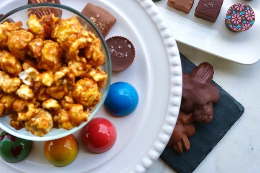 A bowl of popcorn, colorful candies, and chocolate-covered treats on a white plate. 5