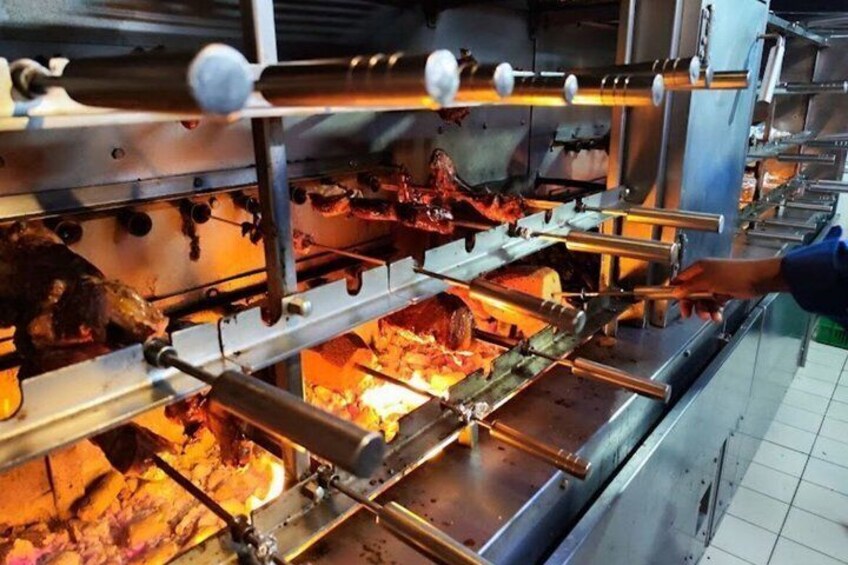 A commercial kitchen with a large industrial oven, cooking racks, and a person adjusting the oven settings. 5