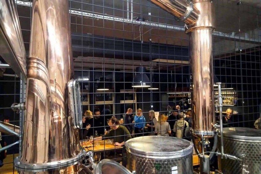 A brewery with copper brewing equipment and a crowd of people. 2