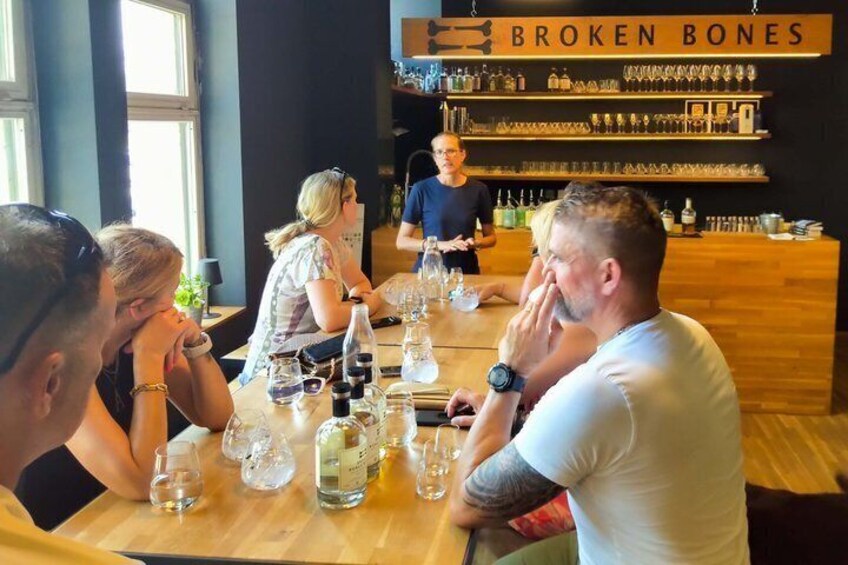 A group of people sitting at a wooden table in a bar with a sign reading 'BROKEN BONES' above the counter. 4
