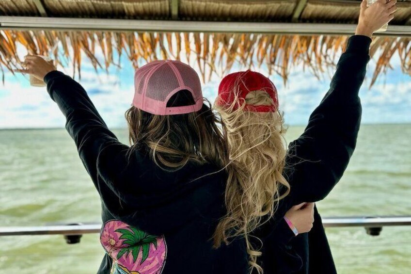 Two people on a boat with a thatched roof, looking out at the water. 1