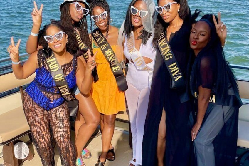 A group of people on a boat with sashes that read 'Sexy & Single' and 'Dancing Diva.' 4