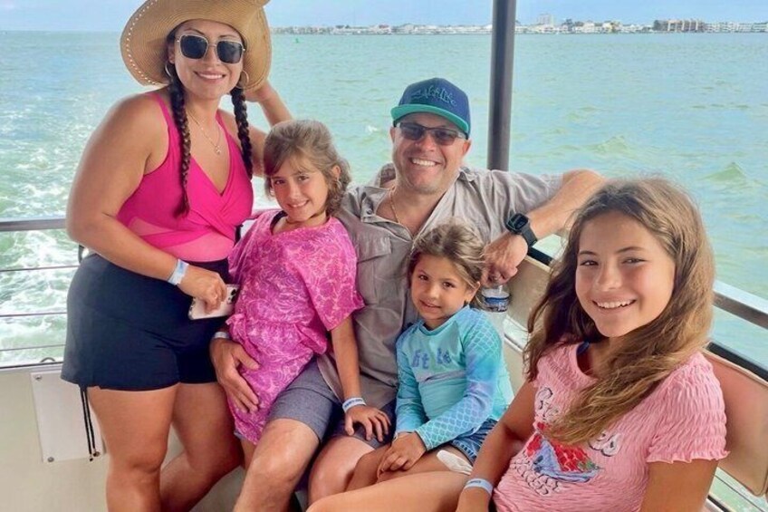 A family on a boat with a body of water and a distant shoreline in the background. 1