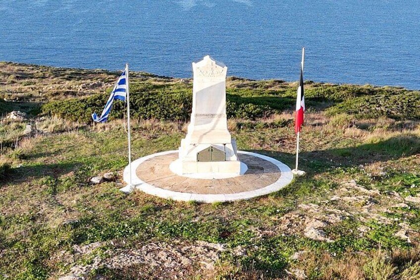 A monument with a circular base, surrounded by grass and a flagpole with a flag. 2