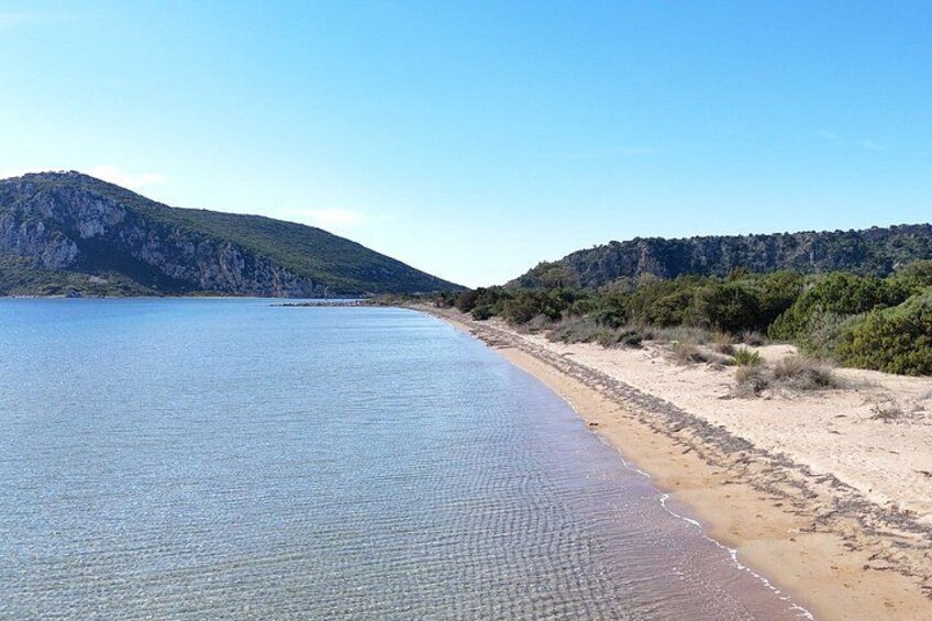 A coastal landscape with a sandy beach, calm sea, and a mountain in the background. 4