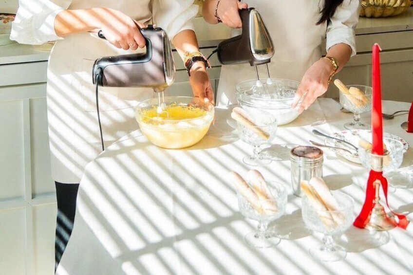 A person pouring a yellow liquid into a glass bowl, with a red candle and a glass jar on the table. 4