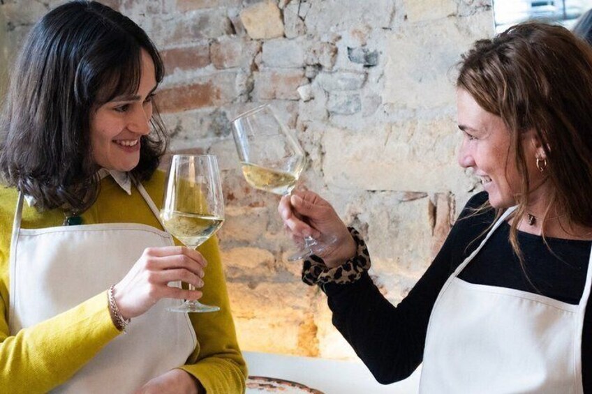 Two people toasting with wine glasses in a rustic setting with stone walls. 2