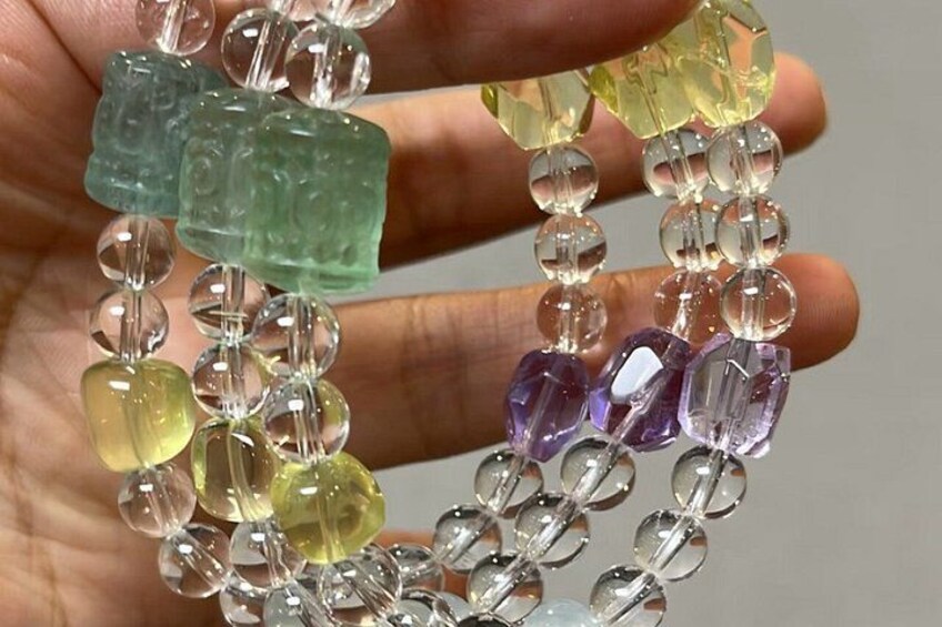 A hand holding a beaded bracelet with variously shaped and colored beads. 3