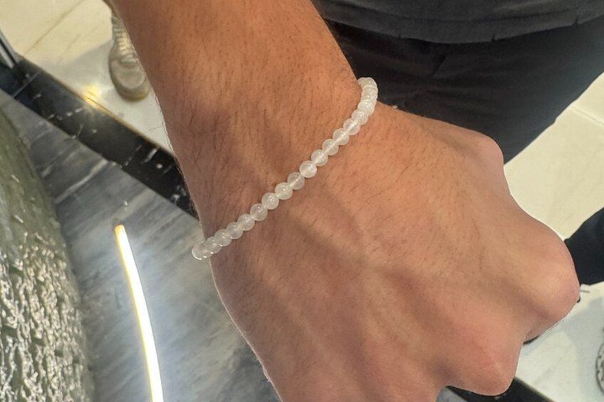 A person's arm wearing a white beaded bracelet. 5