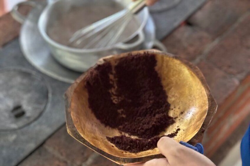 Un cuenco de madera con una mezcla oscura, posiblemente chocolate, sobre una encimera de cocina. 4