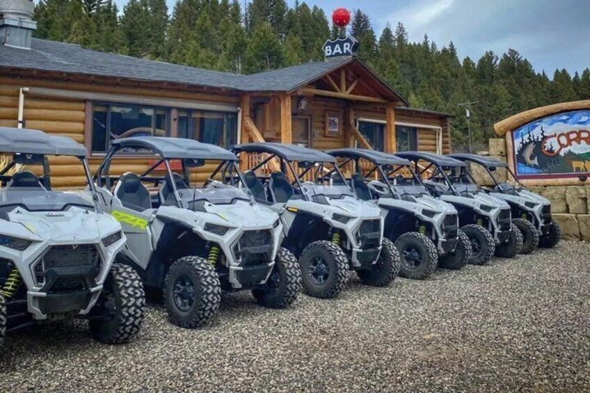 A row of ATVs parked in front of a lodge with a 'BAR' sign above. 5