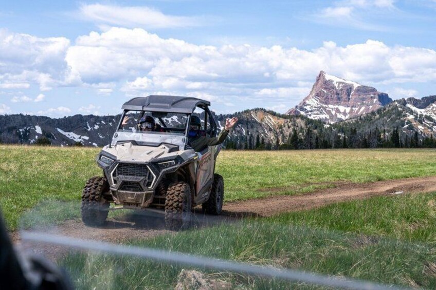A vehicle on a dirt path with mountains in the background. 3