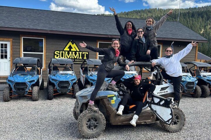A group of people on an ATV with a building labeled 'Summit' in the background. 2