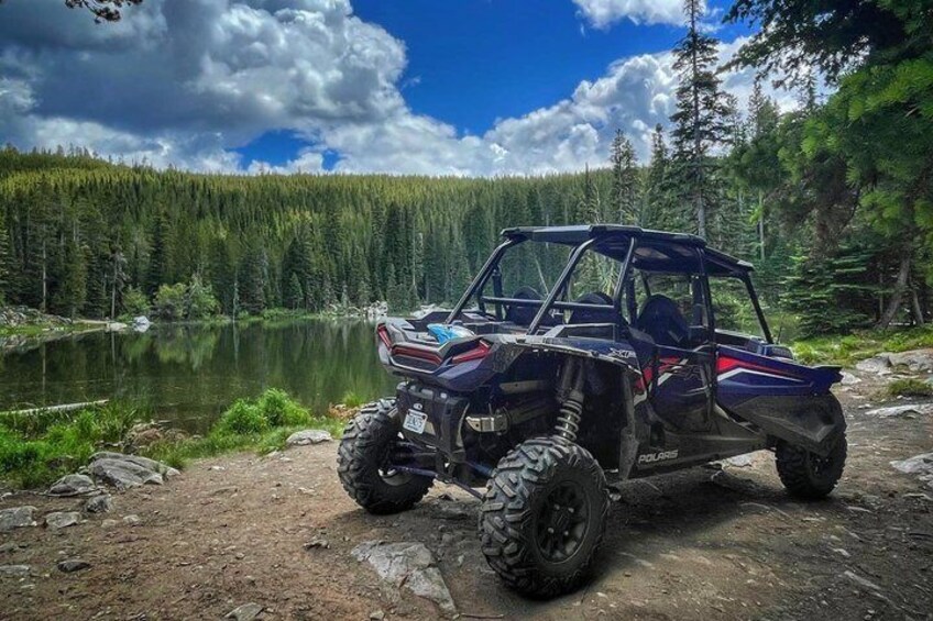 A Polaris ATV parked by a lake surrounded by forest. 3