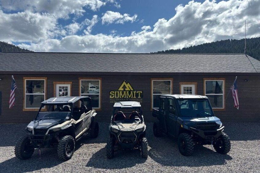 A building with the Summit logo, three ATVs parked in front, and American flags on either side. 3