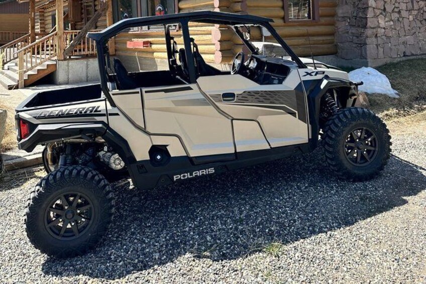 A beige Polaris General off-road vehicle parked on gravel. 5