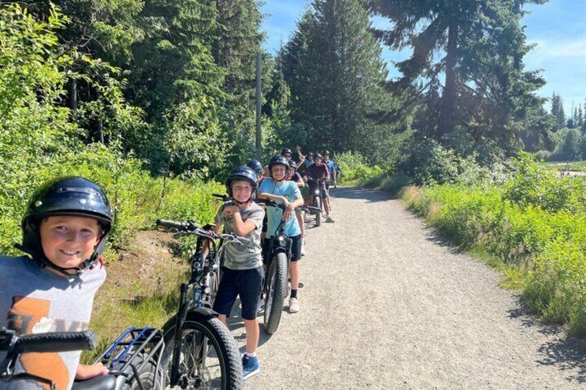 A group of people on bicycles on a gravel path surrounded by greenery. 1