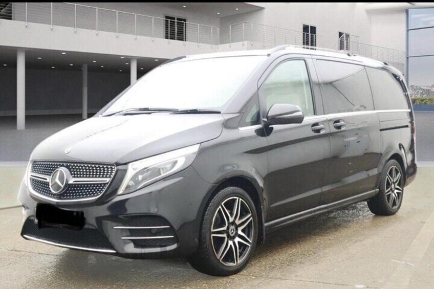 A gray Mercedes-Benz minivan parked in a modern building with a glass facade. 2