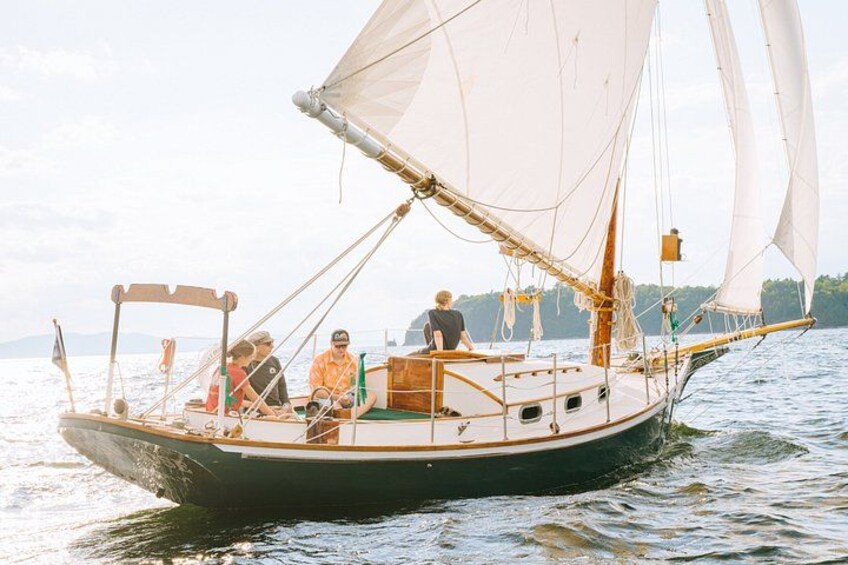 A sailboat with multiple people on board, sailing on a body of water. 3