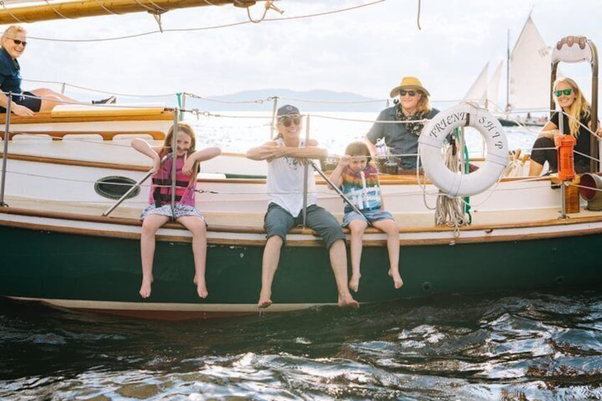 A group of people on a boat with a life preserver and a sail. 3