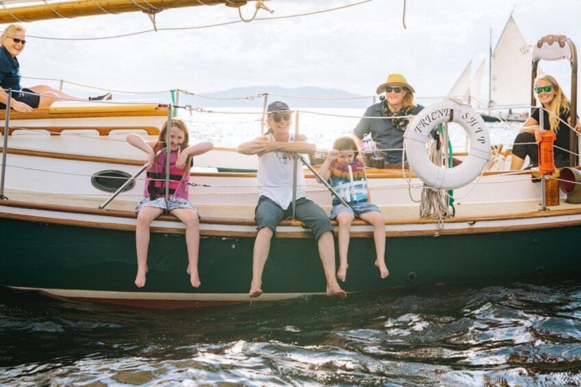 A group of people on a boat with a life preserver and a sail. 4