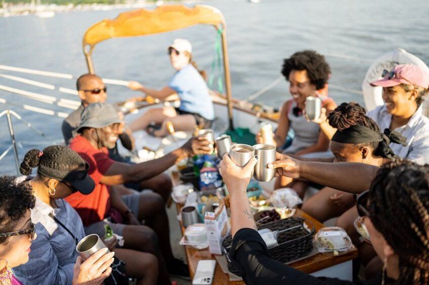 A group of people on a boat, holding cups, likely enjoying a drink. 5
