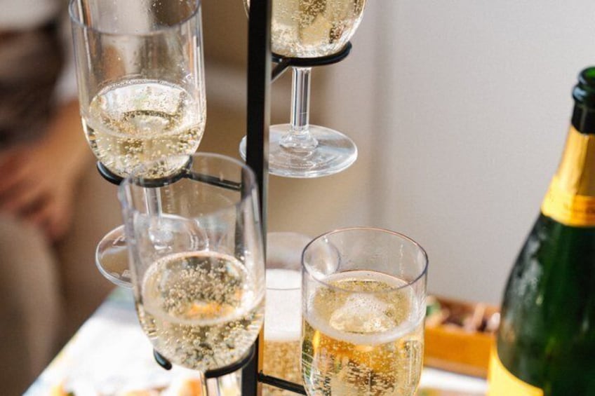 A champagne flute rack with glasses, a bottle of champagne, and a blurred person in the background. 3