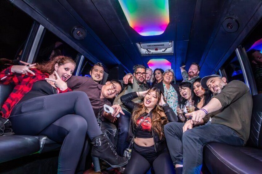 A group of people seated in a vehicle with a sign above them that reads 'SICK ROOM.' 2