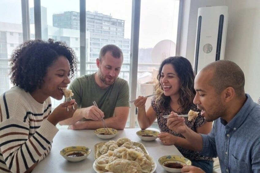 Four people dining at a table with bowls of food and chopsticks. 2