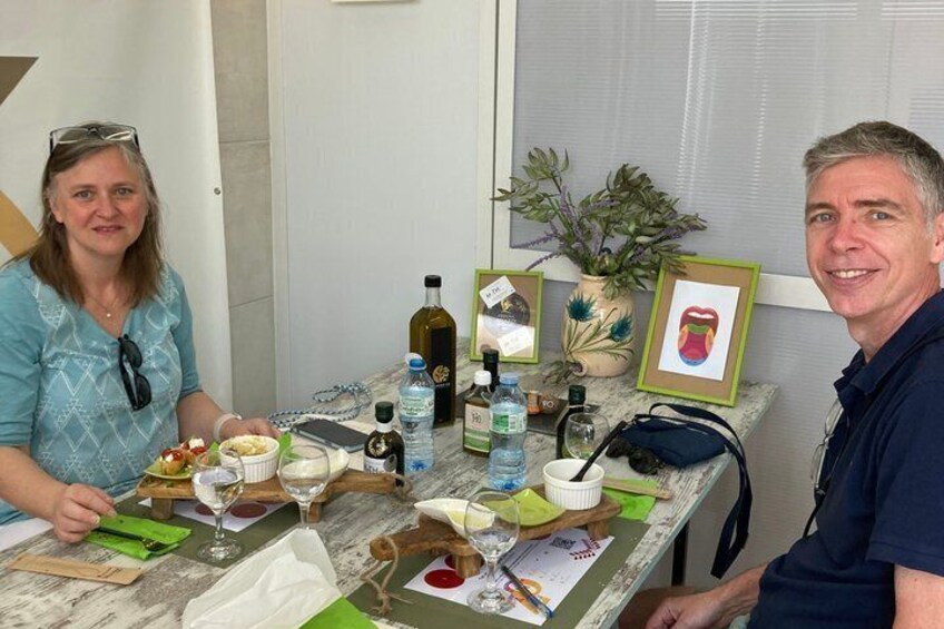 A person sitting at a table with a bottle of olive oil, a glass, and a framed picture. 2