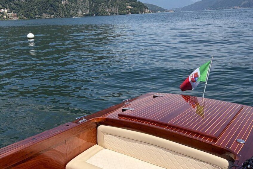 A wooden boat with a flag, calm water, and a distant shoreline. 5