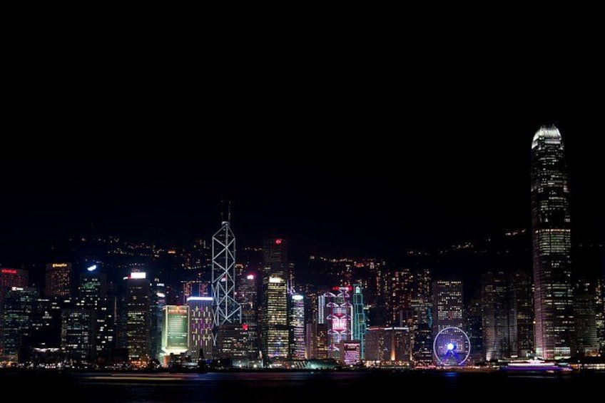 A nighttime city skyline with illuminated buildings and a prominent tower. 5
