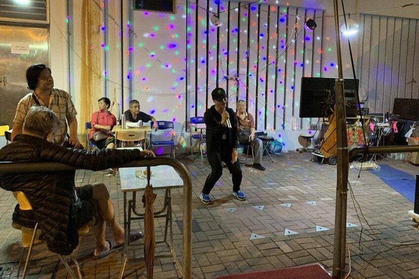 An indoor event with tables and chairs, a person walking, and a stage with musical instruments. 3