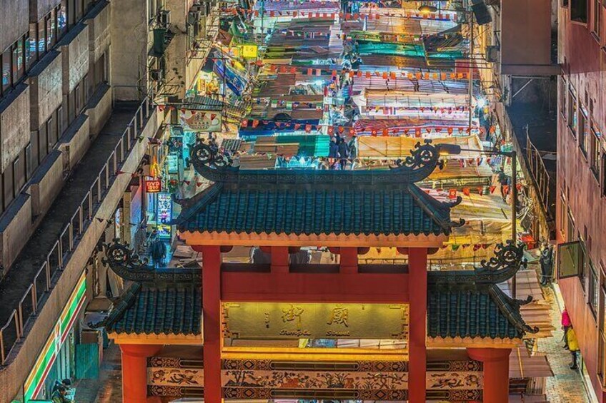 A traditional Chinese architectural structure with ornate roofs and a bustling market area in the background. 5