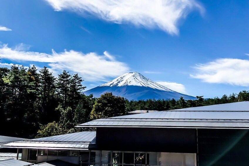 A snow-capped mountain, likely Mount Fuji, under a clear sky with a building in the foreground. 3