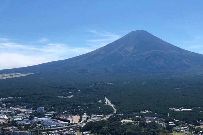 A volcano with a clear sky, a road leading up, and a town in the foreground. 2