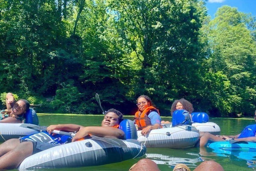 People floating on water in inflatable tubes surrounded by trees. 5